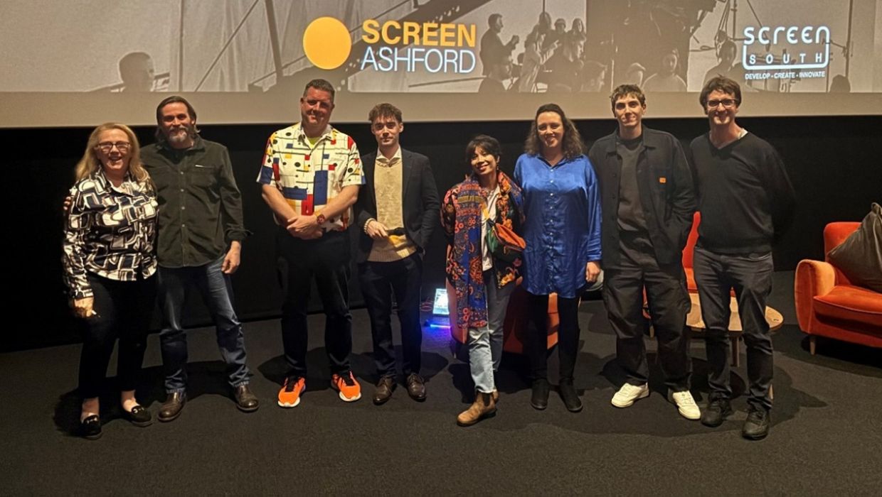 People standing in front of a screen that has 'Screen Ashford' written on in orange