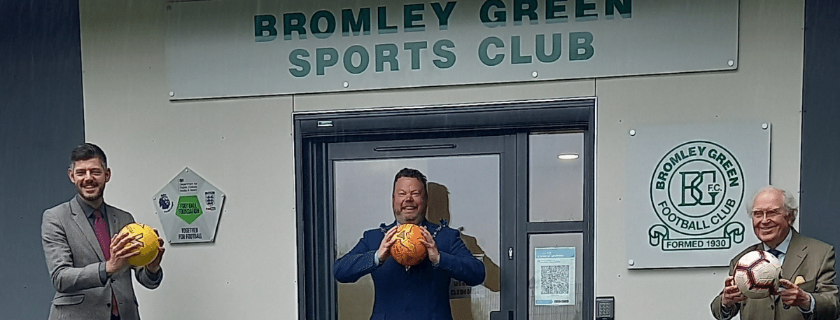 3 Councillors holding football outside a new sports pavilion