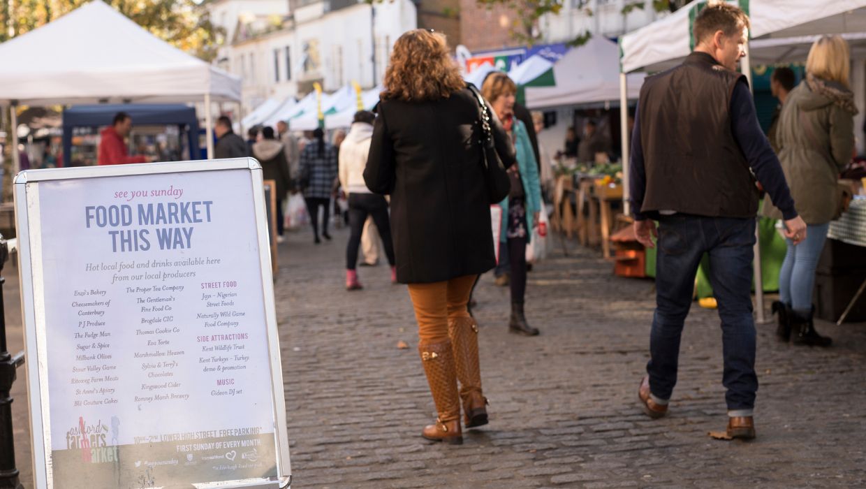 Visitors walking through a market in Ashford Town Centre tile