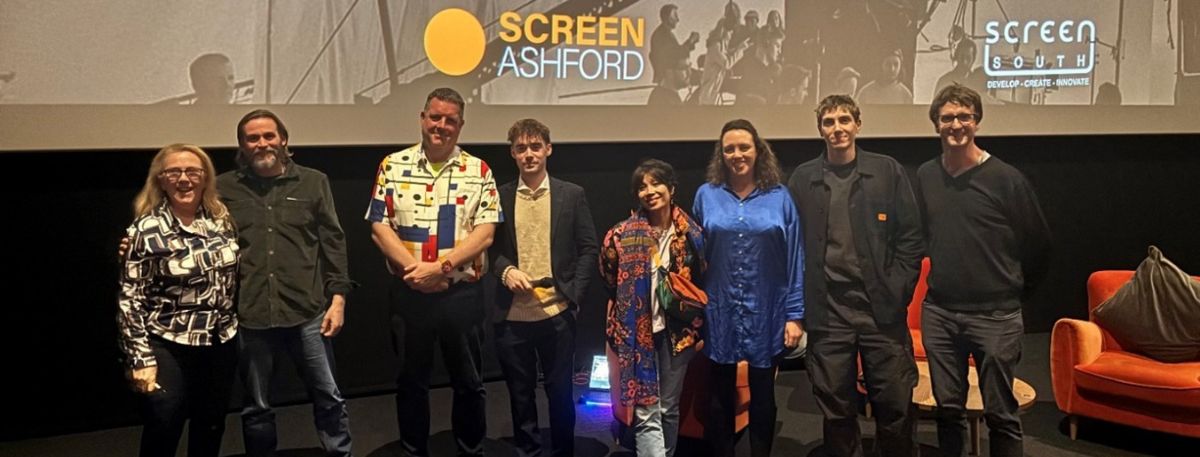 People standing in front of a screen that has 'Screen Ashford' written on in orange