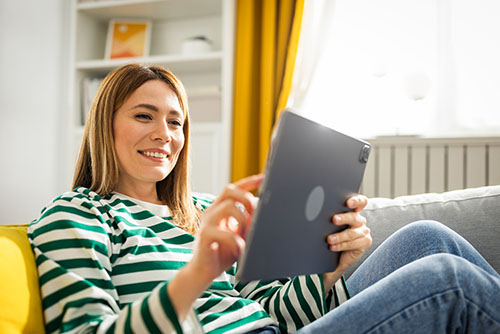 Image entitled woman sitting on sofa with tablet in her hands