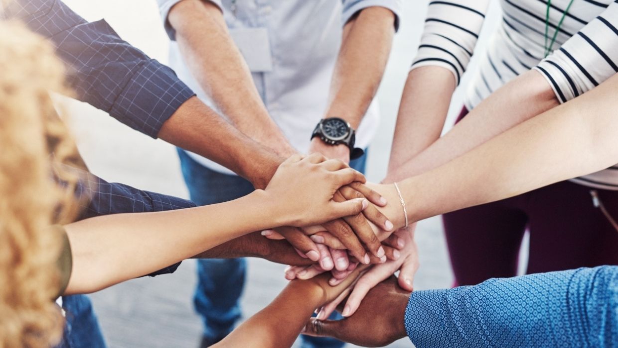 a group of people placing their hands together in unity tile