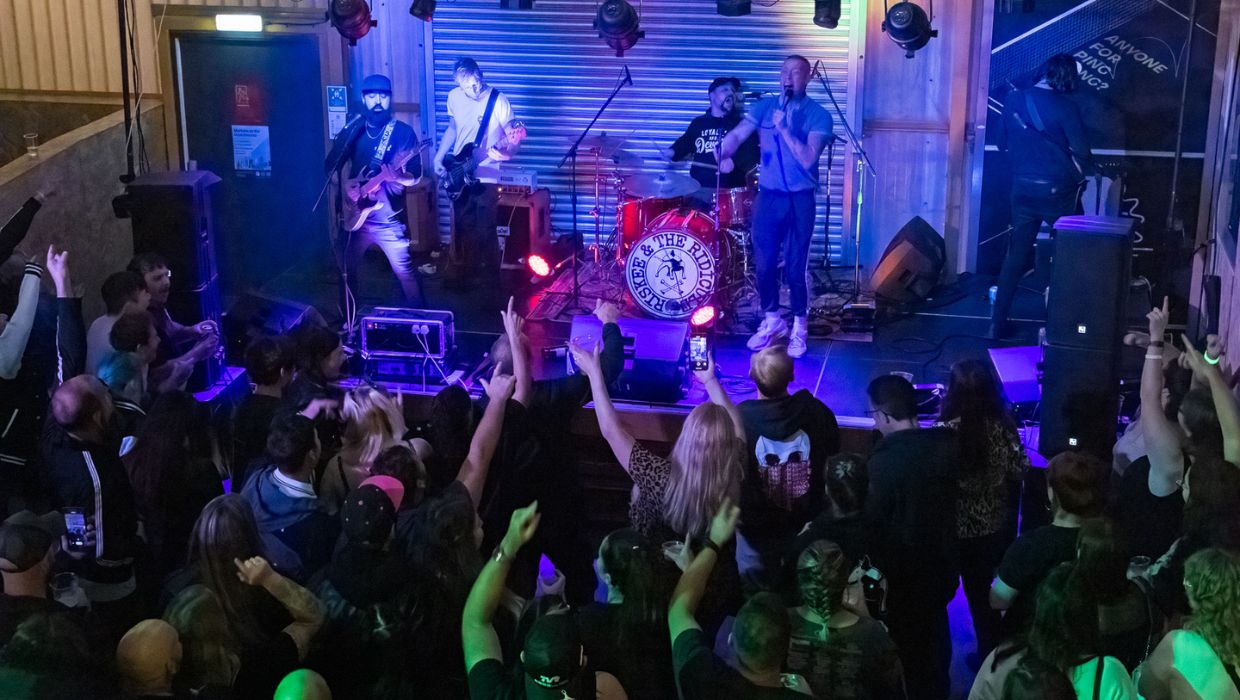 A band on a stage with people watching and singing