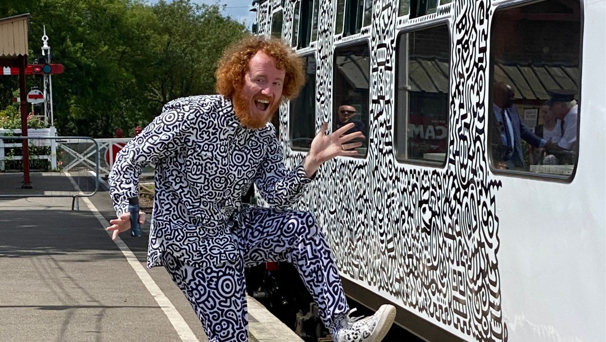 Mr Doodle standing in front of the train carriage with his doodles on it 