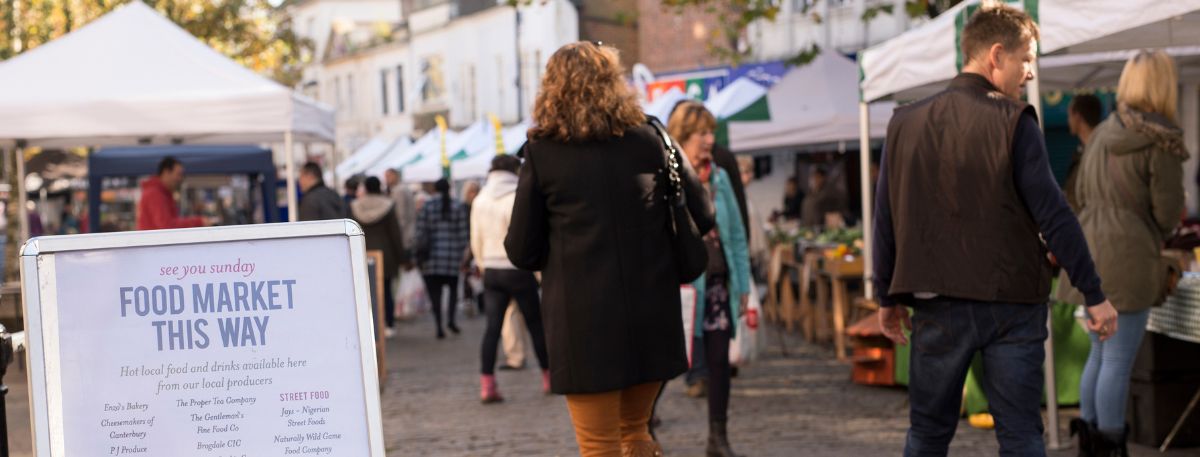 Visitors walking through a market in Ashford Town Centre