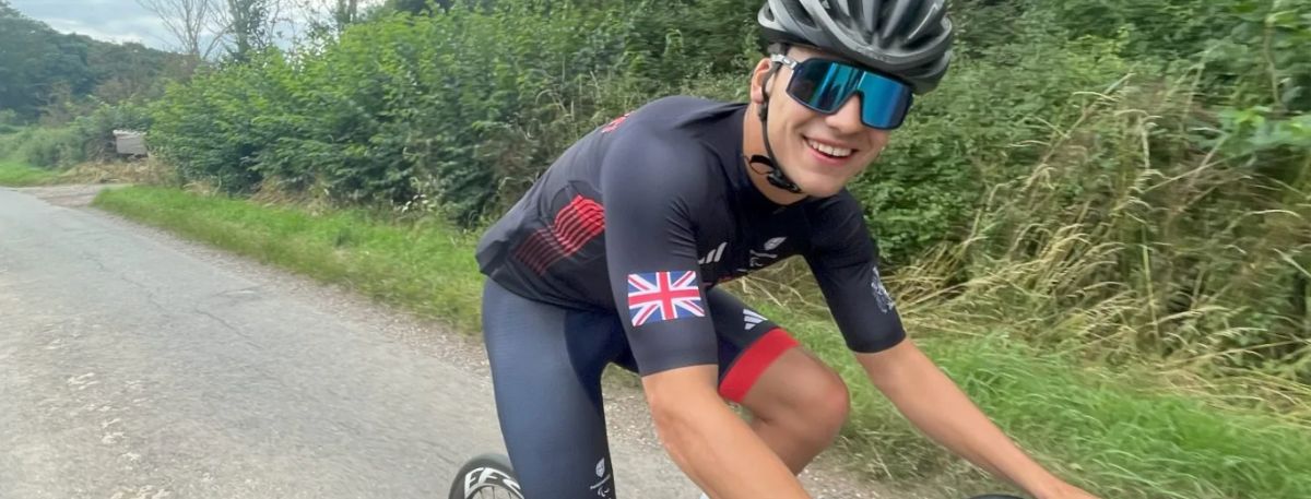 Image of a man cycling on a road wearing a helmet and Great Britain kit