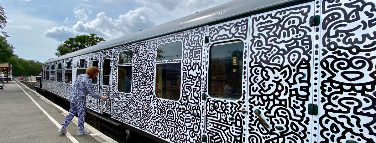 Mr Doodle standing in front of the train carriage with his doodles on it 