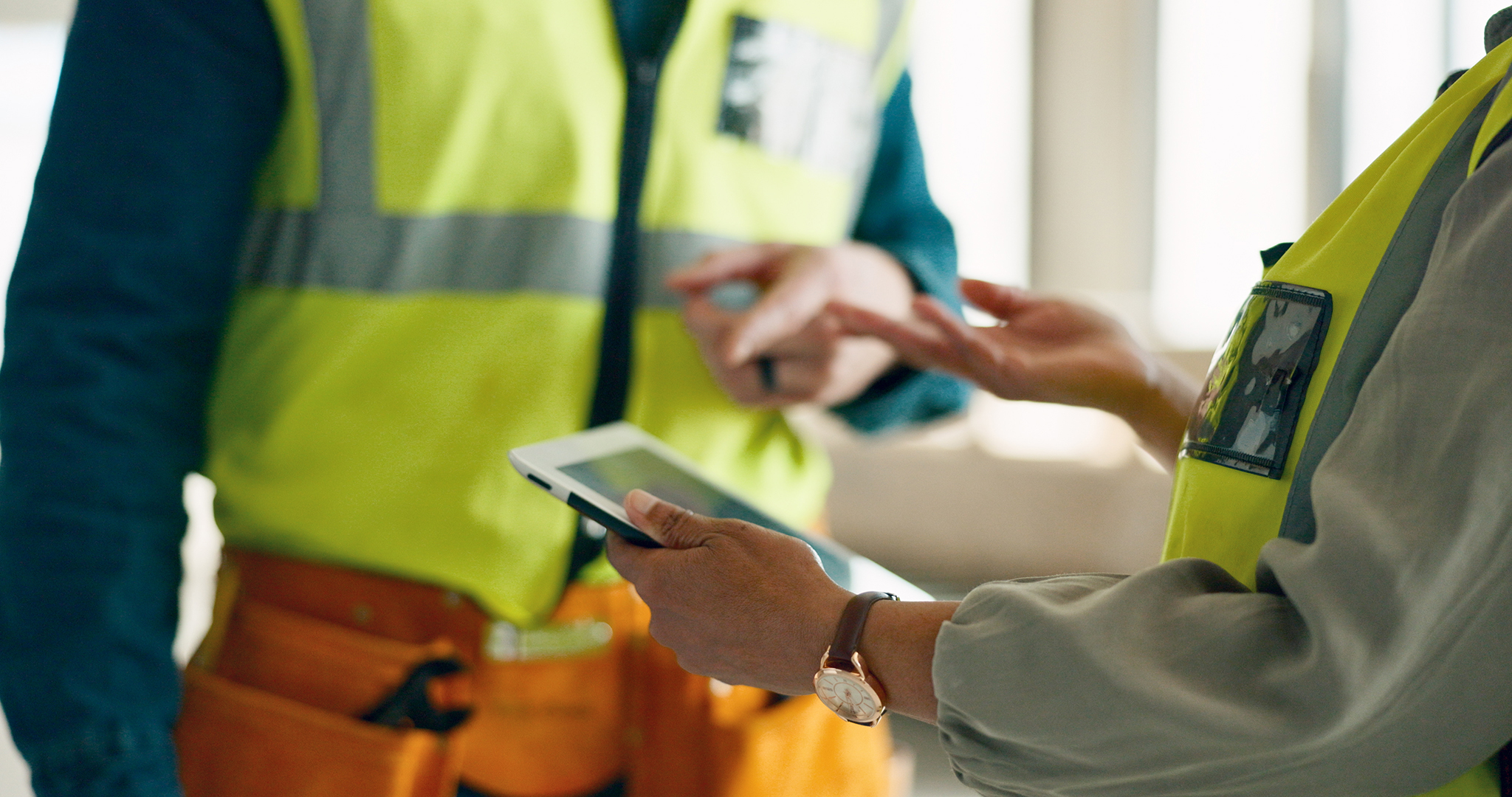 Image entitled close up of two people in hi vis vests with ipad.