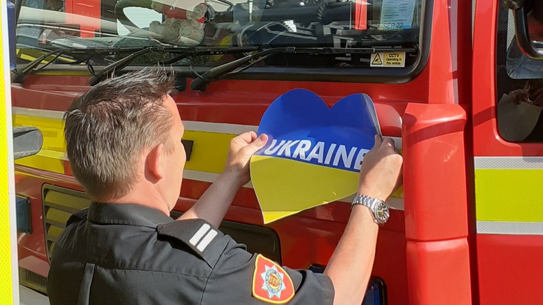 man putting a Ukraine heart sticker on a fire engine.jpg