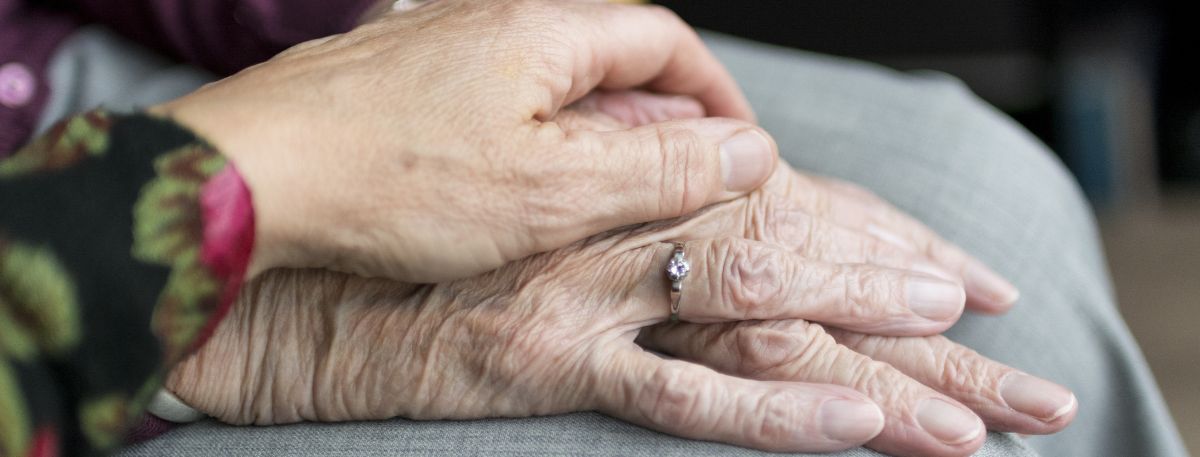 Person putting a hand on an elderly person's hand